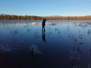 Man standing by lake against sky