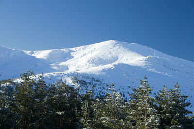 Scenic view of snowcapped mountains against clear blue sky