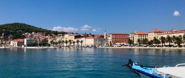 Scenic view of sea by buildings in town against sky