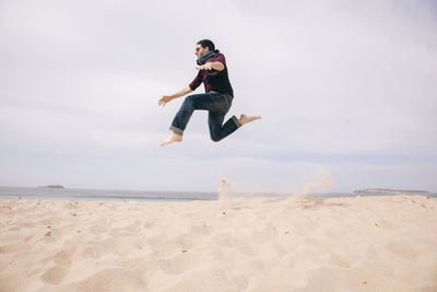 Full length of young man jumping on beach