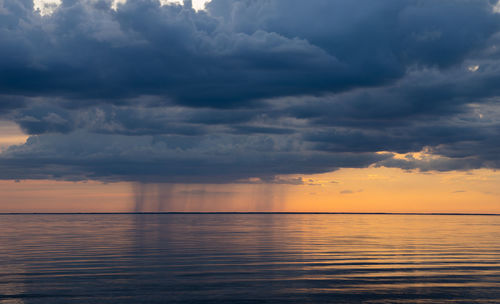 Scenic view of sea against dramatic sky during sunset