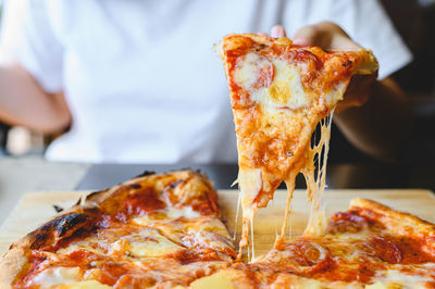 Close-up of hand holding pizza