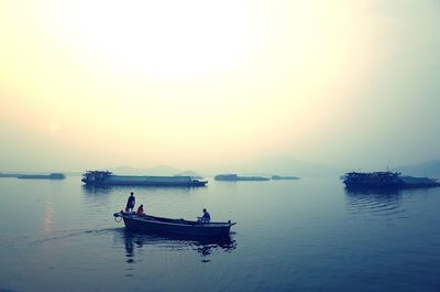 Boats in sea at sunset