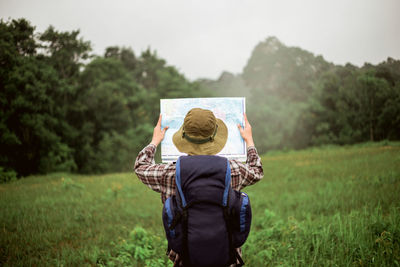 Rear view of man reading map while standing on land
