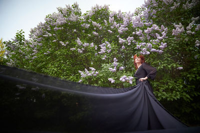 Low angle view of woman standing against trees