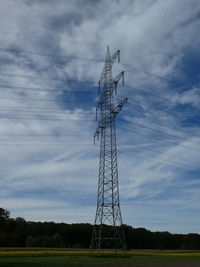 Low angle view of electricity pylon on field against sky