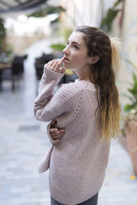 Beautiful teenage girl wearing sweater standing in city