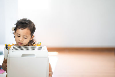 Cute little girl standing breathing at air purifier. pollution concept.