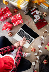 Directly above shot of young woman using laptop by christmas decoration