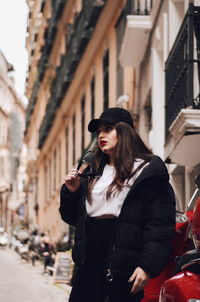 Young woman holding umbrella standing in city