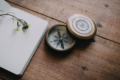 Old compass on wooden table next to notebook