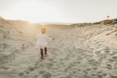 Young girl walking away at beach during sunset