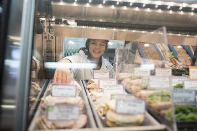 Female worker arranging food in display cabinet at supermarket