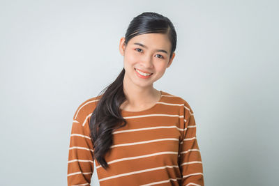 Portrait of smiling young woman against white background