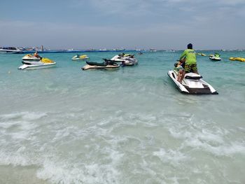 People on boat in sea against sky