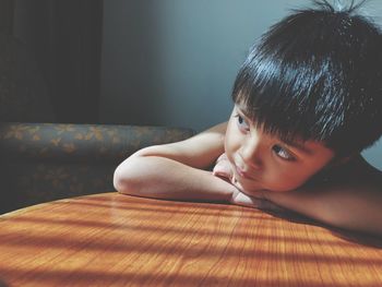 Cute boy looking away at table in home