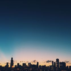 Illuminated cityscape against clear blue sky