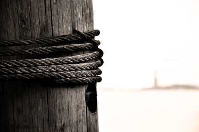 Close-up of rope on wooden post against sky