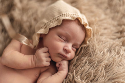 A newborn baby sleeping peacefully in a brown hat. newborn session concept