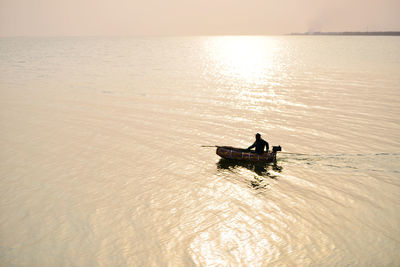 Silhouette man in boat on sea against sky