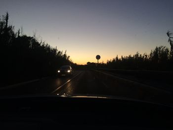 Cars moving on road against sky during sunset