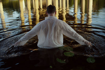 Rear view of man standing by lake