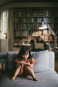 Down syndrome girl using mobile phone on sofa at home