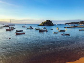 Boats moored in sea at sunset