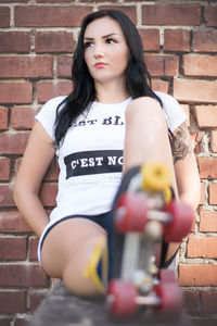 Portrait of young woman leaning on brick wall