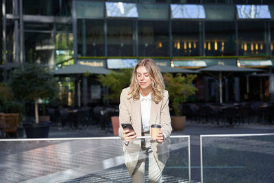 Portrait of young woman standing in city