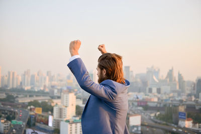 Rear view of woman standing on city against clear sky