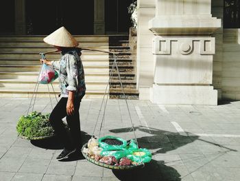 Woman holding umbrella on sidewalk by footpath