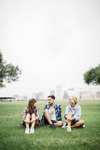 Friends sitting on grassy field