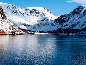 Scenic view of frozen lake by snowcapped mountains against sky