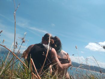 Rear view of couple sitting on land against sky