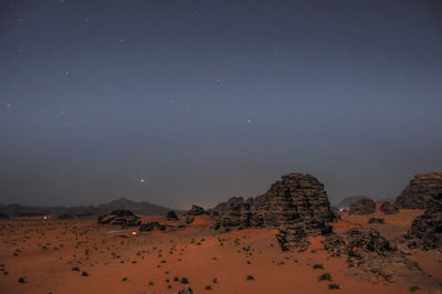 Scenic view of rocks in desert against starry sky