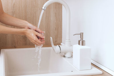 Cropped hands washing sink