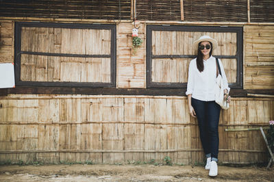 Portrait of woman in sunglasses standing against barn