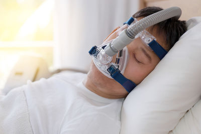 Midsection of man wearing mask in bed