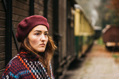 Portrait of young woman standing against a steam train, while enjoying a trip on a beautiful autumn 