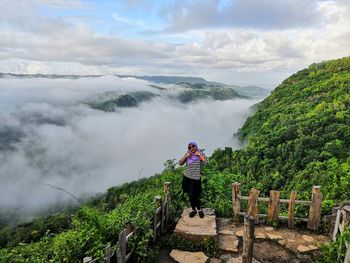 Rear view of woman standing on mountain against sky