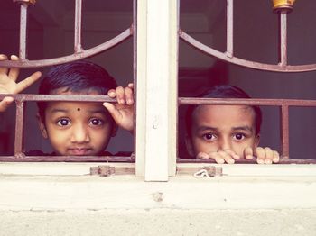 Portrait of siblings peeking through window