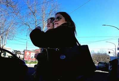 Beautiful woman standing by car against sky