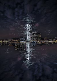 Illuminated modern buildings in city against sky at night