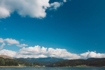 Scenic view of lake and mountains against blue sky