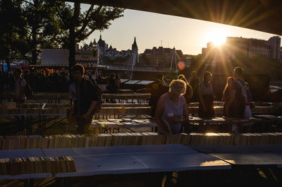 People sitting in city against sky during sunset