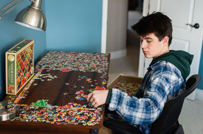 Teen boy working on a jigsaw puzzle in his bedroom during covid 19.