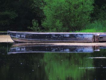 Boat moored on lake against trees