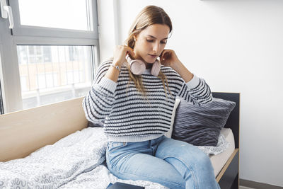 Young woman using phone while sitting on sofa at home