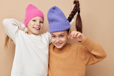 Portrait of sibling against beige backgrounds